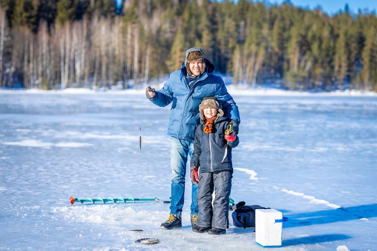 Father and son on the winter fishing at the frozen lake Father and son on the winter fishing at the frozen lake